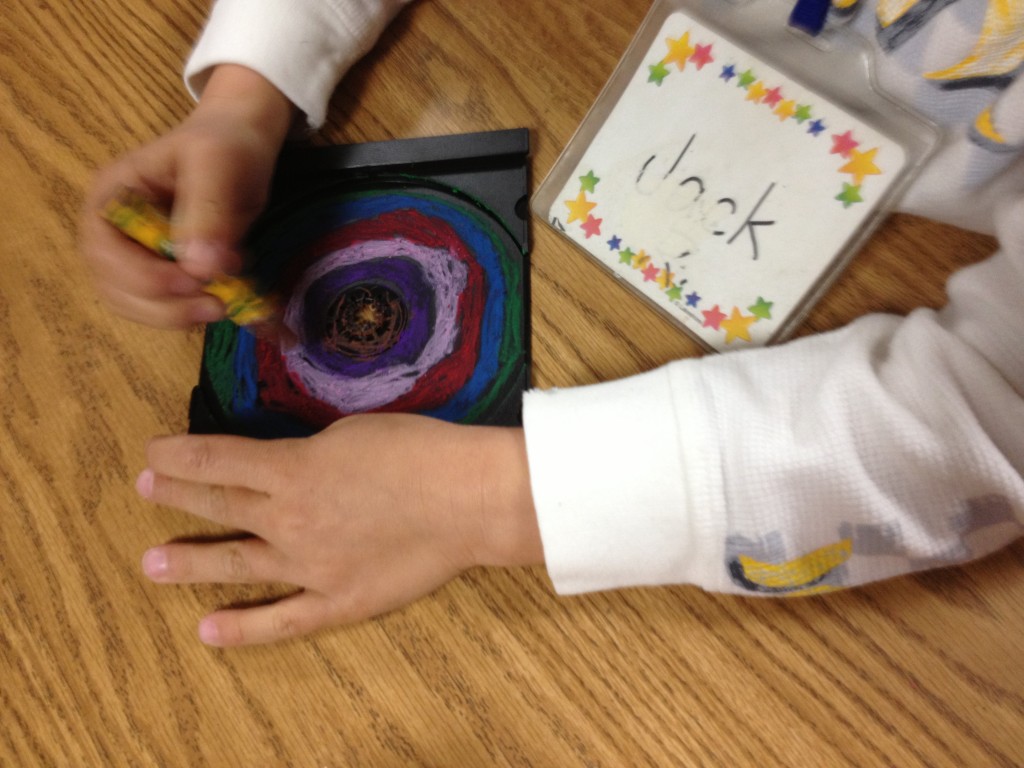 Kindergarteners use oil pastels to draw concentric circles in CD inserts. Allow one 40 minute class, plus time to assemble mural.